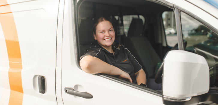 Maintenance-image Smiling woman in Urban Services van driver's seat on Our Services page